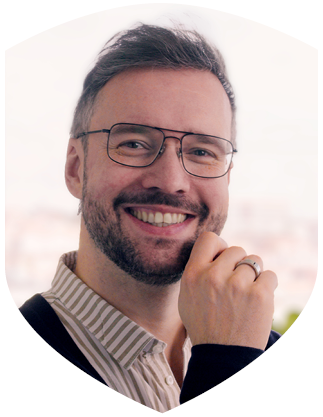 Frank Lauterbach, Inhaber der lauterbach kreativbetreuung, Blick in die Kamera. Er trägt ein gestreiftes Hemd und eine Brille. Seine rechte Hand berührt das Kinn